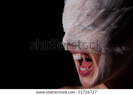 Girl\'s face wound with bandage with a teeth as at the vampire on a black background