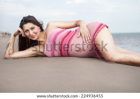 Pregnant woman in white bikini posing on the beach