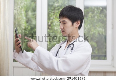 Doctor and modern technology, hand in a white coat points a finger in the tablet PC
