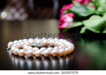 pearl necklace on the table with roses flowers