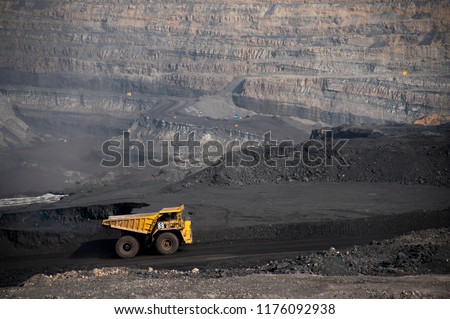 Big yellow mining truck hauling rock in dusty coal mine