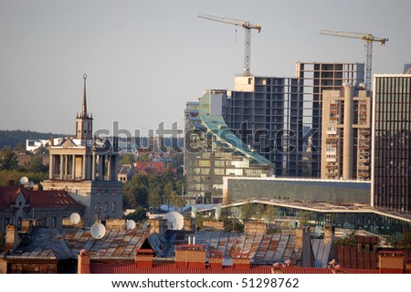 Skyscrapers being built, next to a building from middle of 20 century, rising high above average city rooftops. New vs. old, vertical vs. horizontal, glass vs. concrete. Vilnius, Lithuania, 2009
