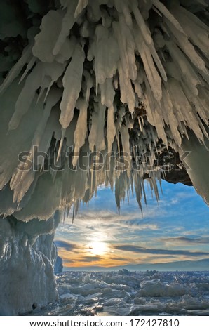 Baikal Lake in winter. Icy cave in a rocky island at sunset