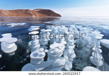 Baikal Lake. Unusual winter landscape. White layered bubbles in transparent ice