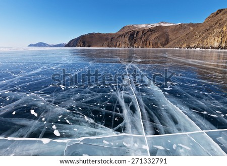 Frozen Lake Baikal. Beautiful winter landscape with clear smooth ice near rocky shore