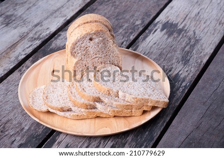 Sliced whole wheat bread in wood dish on table.