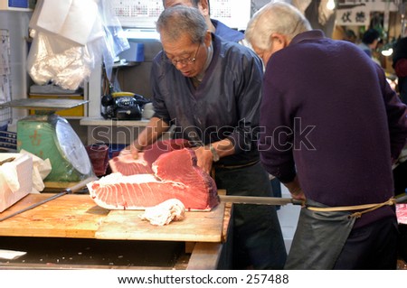 Worker in Tsukiji fish market, Tokyo, Japan. Carving  fresh tuna
