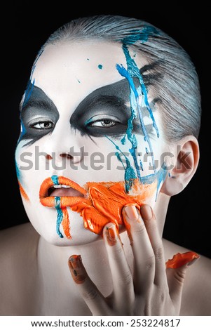 Close portrait of a girl with smeared paint on the face with your fingers.
