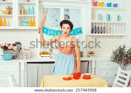 Pin-up girl style. Girl standing in the kitchen and brandishing a rolling pin for the dough.