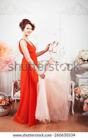 Girl touching tenderly pink ballet dress, hanging near pointe.