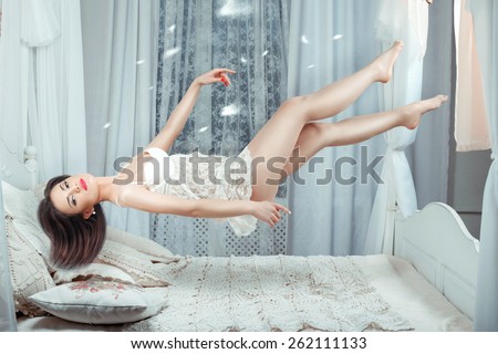 Cute girl hovers over the bed in the air without touching the bed.