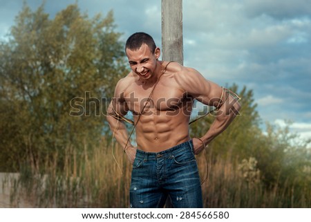 Man with large muscles attached to the pillar. He tries to break free.
