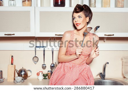 The woman in the kitchen. In the hands holding tools for cooking food. She flirts.