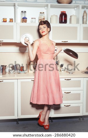 Girl standing in the kitchen in the hands holding a pan and cover. She dreams of cooking.