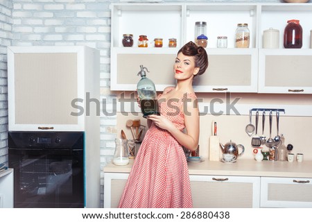 She is the mistress of the kitchen. In her hands she holds a bottle. She smiles.