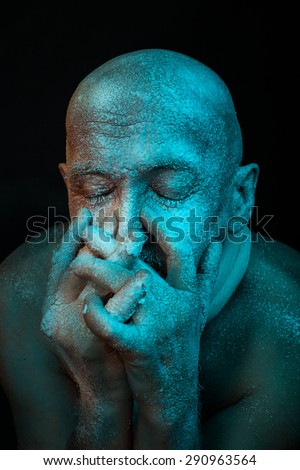 Bald man put his hands to his face. He is cold and it is covered with frost.