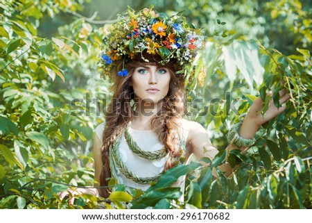 Close-up portrait of a girl. It is among the leaves of the trees with a wreath on his head.