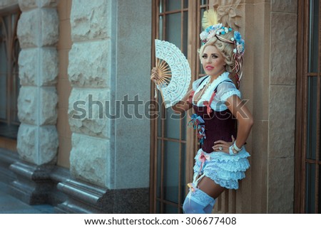 Girl in old clothes and vintage hair on his head. The fan in her hand.