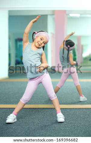 Kid doing fitness exercises near mirror