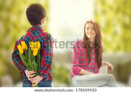 Rear view lad with bunch of beautiful tulips behind back preparing nice surprise for his mother . Mother`s day concept. Family holiday