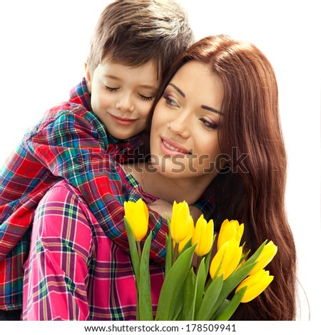 Son hugging happy mother with flowers. Mother`s day concept. Family holiday. Isolated on white background
