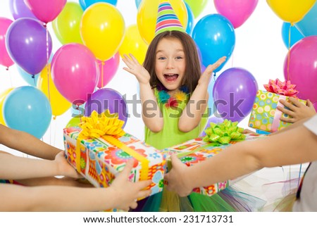 Joyful little kid girl receiving gifts at birthday party. Holidays, birthday concept.