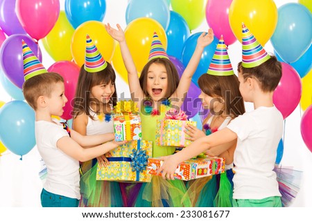 Joyful little kid girl receiving gifts at birthday party. Holidays, birthday concept.