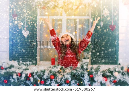 Merry Christmas and Happy Holidays! Happy child girl stretches her hand to catch falling snowflakes. First snow. Winter magic