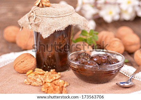 Jam-jar of walnuts on a wooden background