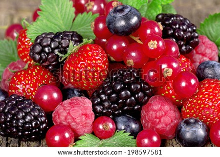 Fresh berries with mint leaves on a wooden background