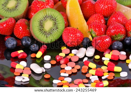 Berries, fruits, vitamins and nutritional supplements on a  black  background