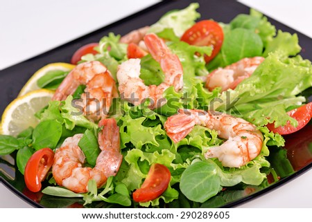 Lettuce with shrimp and tomatoes on a black background