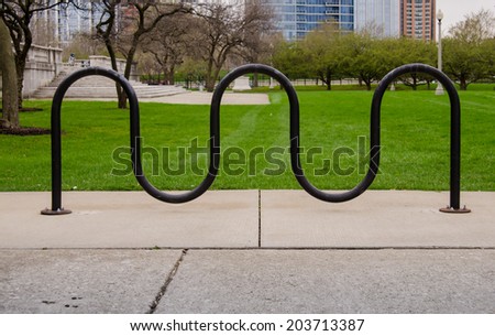 A bike rack sits in front of green grass in a public space
