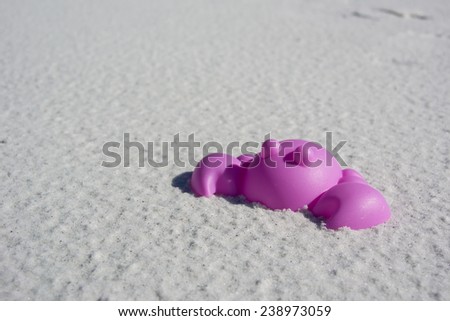 A plastic purple crab sand toy on soft white sand