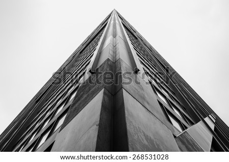 Looking up the corner of a skyscraper building on an overcast day