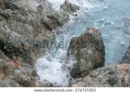 The aqua waters of the Caribbean splashing against a rocky coast
