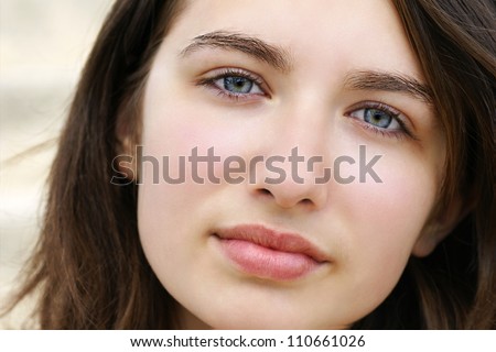 Portrait of a beautiful young woman, teenager or student with stunning light blue eyes and fair skin, looking serious, sad or aloof looking at camera.