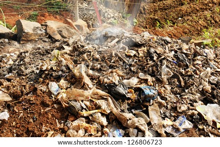 Pile of rubbish, garbage and various products, including lots of plastic, being burnt as a form of waste management in a third world country.