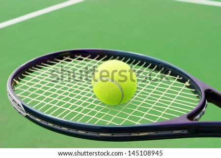 Tennis racket with ball on hard surface court