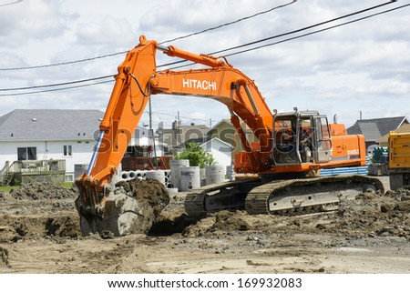 CANADA, QUEBEC, June, 20, 2011: New Hitachi orange digger used to put up new sewer lines. Hitachi is a Japanese multinational with part of their products being construction machinery.