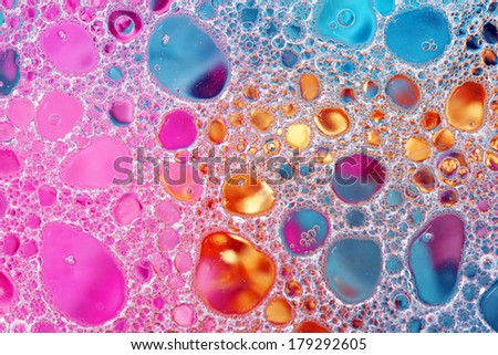Oil and water over colorful pink, gold and blue background