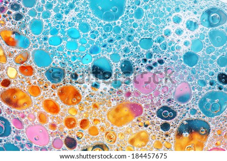 Oil drop and water over colorful pink, gold and blue background