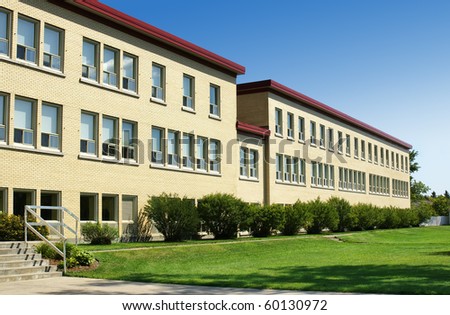 Old school or hospital wing made of yellow bricks, with green grass and blue sky.
