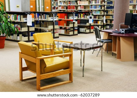 Reading area and computers at a university/college school library. Colorful yellow leather chairs.