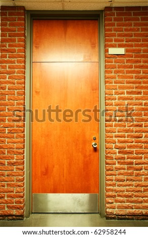 Office building or school wood door in olive green metal frame in terra cotta brick wall.