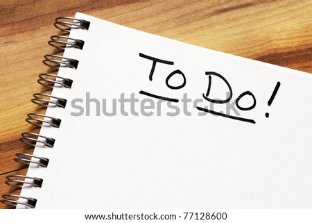 Blank textured white page of a spiral notebook with the title To Do in black ink marker on wood background, ready for your text.