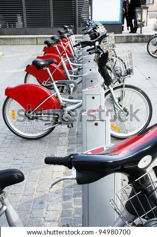Alternative transportation: Bicycles for rent parked at a station in front of a bus stop in old european city.