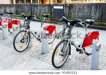 Alternative transportation: Bicycles for rent parked at a station in front of concrete wall in old european city.