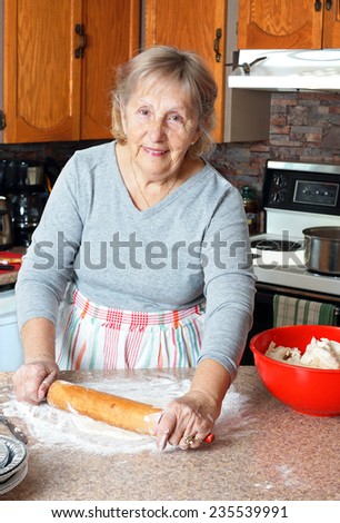 Senior woman or grandma rolling dough to make pies in her kitchen