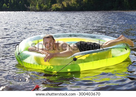 Man having fun and relaxing on large plastic buoy or swim ring at the lake